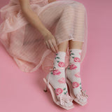 Person wearing floral high-heeled shoes and socks on a pink background