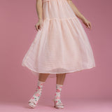 Person wearing a pink dress and floral socks on a pink background