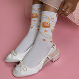 White socks with heart and chain design worn with white shoes on a pink background thumbnail