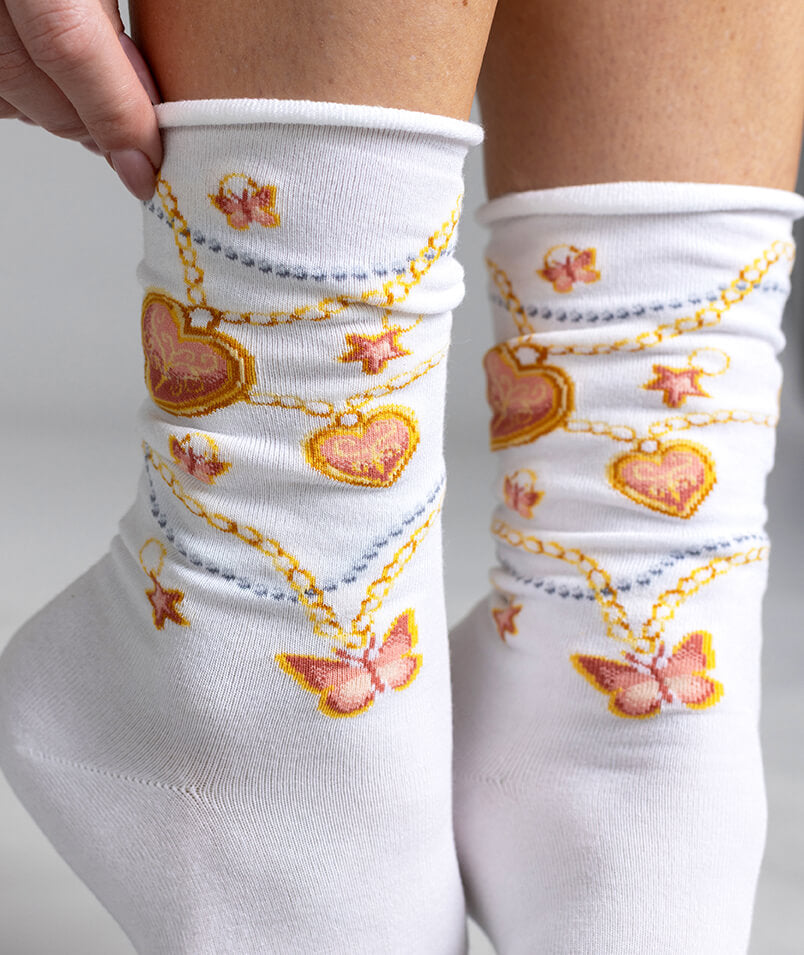 White socks with decorative patterns of hearts, chains, and butterflies on a plain background