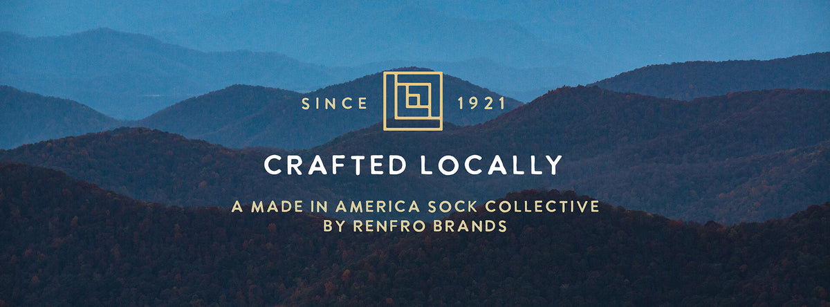A scenic graphic with layered blue mountain ranges under a dark blue sky, overlaid with gold text reading 'SINCE 1921', 'CRAFTED LOCALLY', and 'A MADE IN AMERICA SOCK COLLECTIVE BY RENFRO BRANDS'.