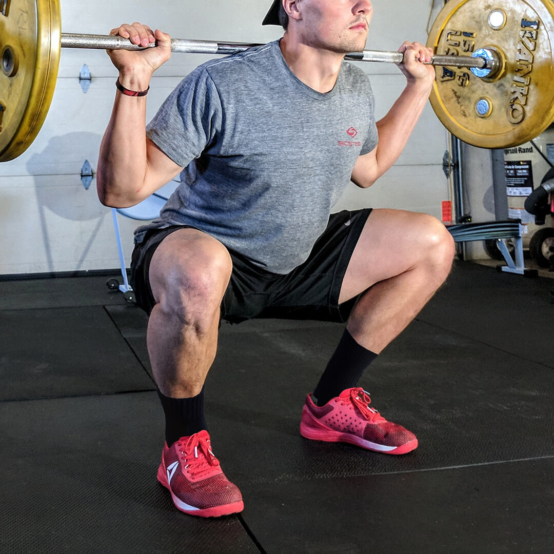 Person performing a barbell squat in a gym setting