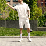 Person wearing a white outfit standing outdoors with greenery in the background thumbnail