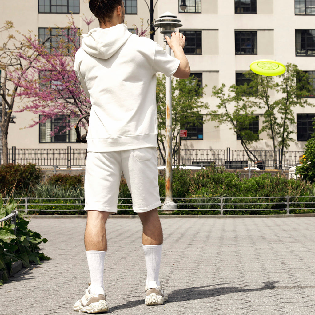 Person in white outfit playing with a yellow frisbee in an urban park setting