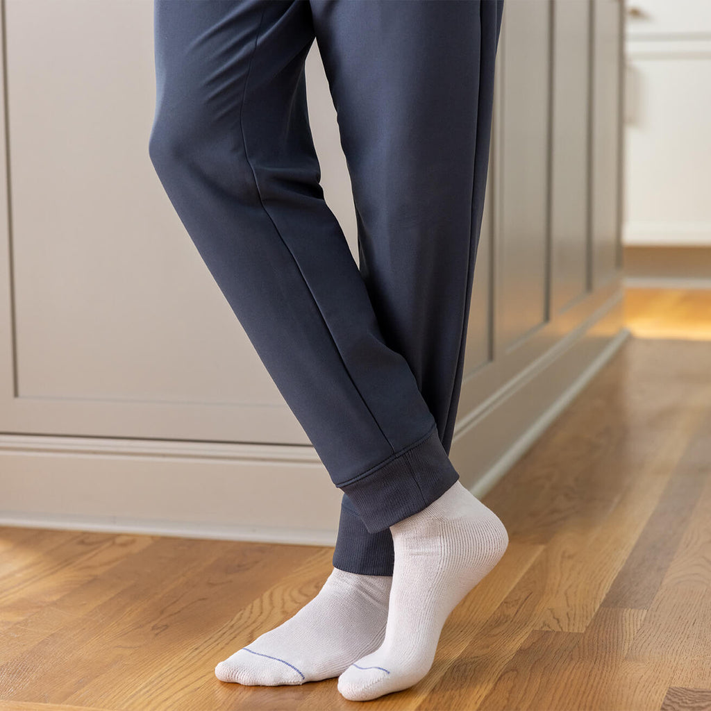 Person wearing navy pants and white socks on a wooden floor.