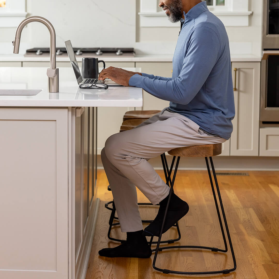 Man using a laptop at a kitchen counter on a stool