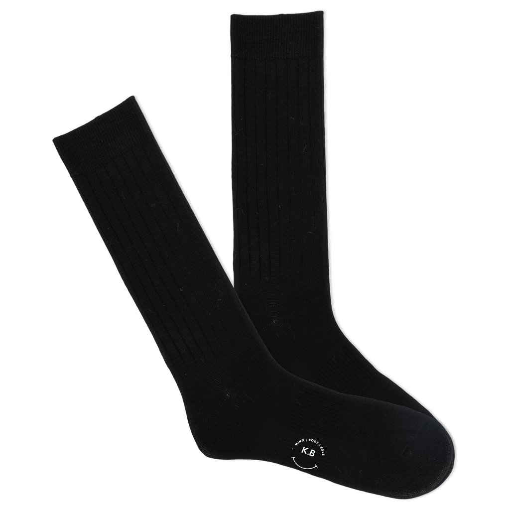 A pair of black ribbed crew socks with a visible K.Bell brand logo on the sole.