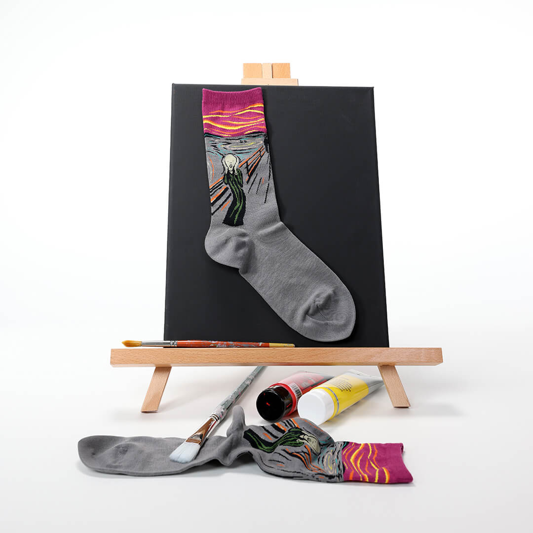 Gray sock with a colorful design on an easel with art supplies