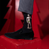 Black sock with a graphic design of a muscular figure holding a flower, worn with a black shoe on a red surface. thumbnail