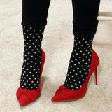 Red high-heeled shoes with black polka dot socks on a neutral background thumbnail