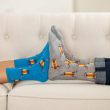 Two pairs of socks, one blue and one gray, with hot dog pattern on a light-colored couch.