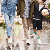 Three people walking on a wet street, with one person holding a soccer ball.