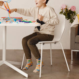 Child sitting at a table playing with colorful toys in a room with a couch and flowers.