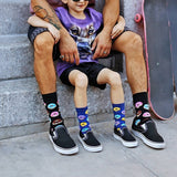Person and child sitting on steps wearing colorful socks with donut and rainbow designs. thumbnail