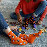 Two children sitting on the floor with Halloween-themed socks and candy. thumbnail