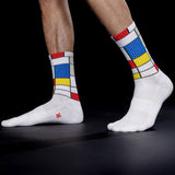 White socks with colorful Mondrian pattern worn by a person on a black background