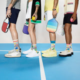 Four people standing on a pickleball court with colorful equipment and socks. thumbnail