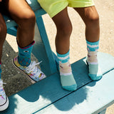 Two pairs of legs wearing colorful socks and shoes on a blue bench.