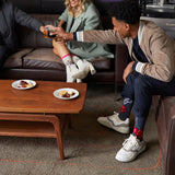 Three people sitting on a couch with a coffee table in front of them, enjoying snacks and drinks.