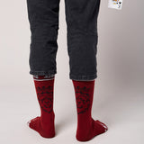 Red socks with black lion pattern worn by a person against a neutral background