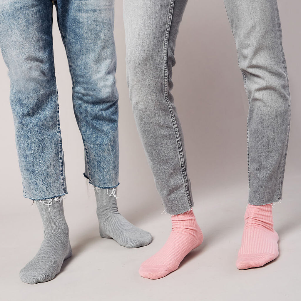 Two pairs of jeans worn by different people on a plain background