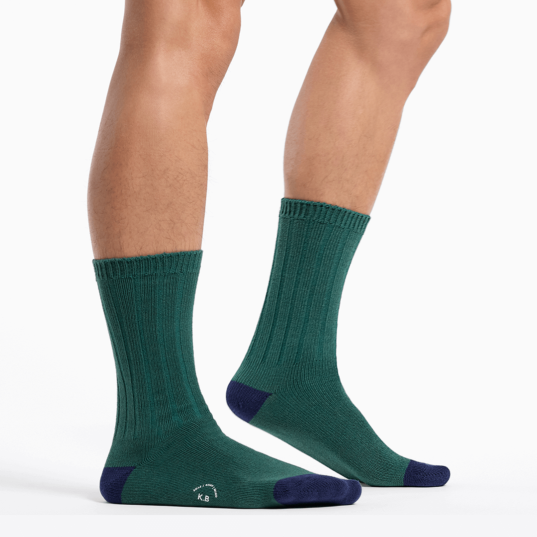 Green socks with navy toes and heels worn by a person on a white background