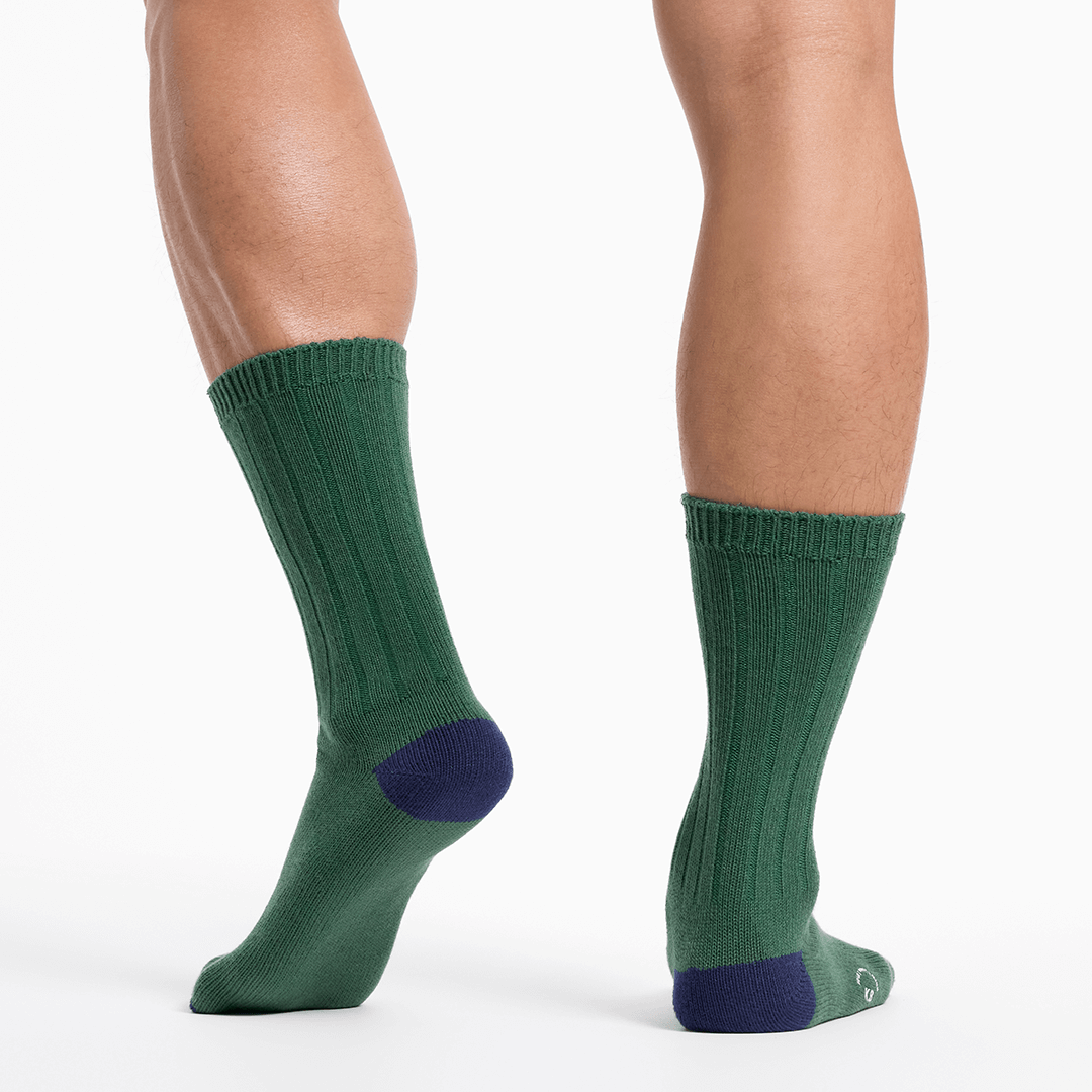 Green socks with navy toes and heels worn by a person on a white background