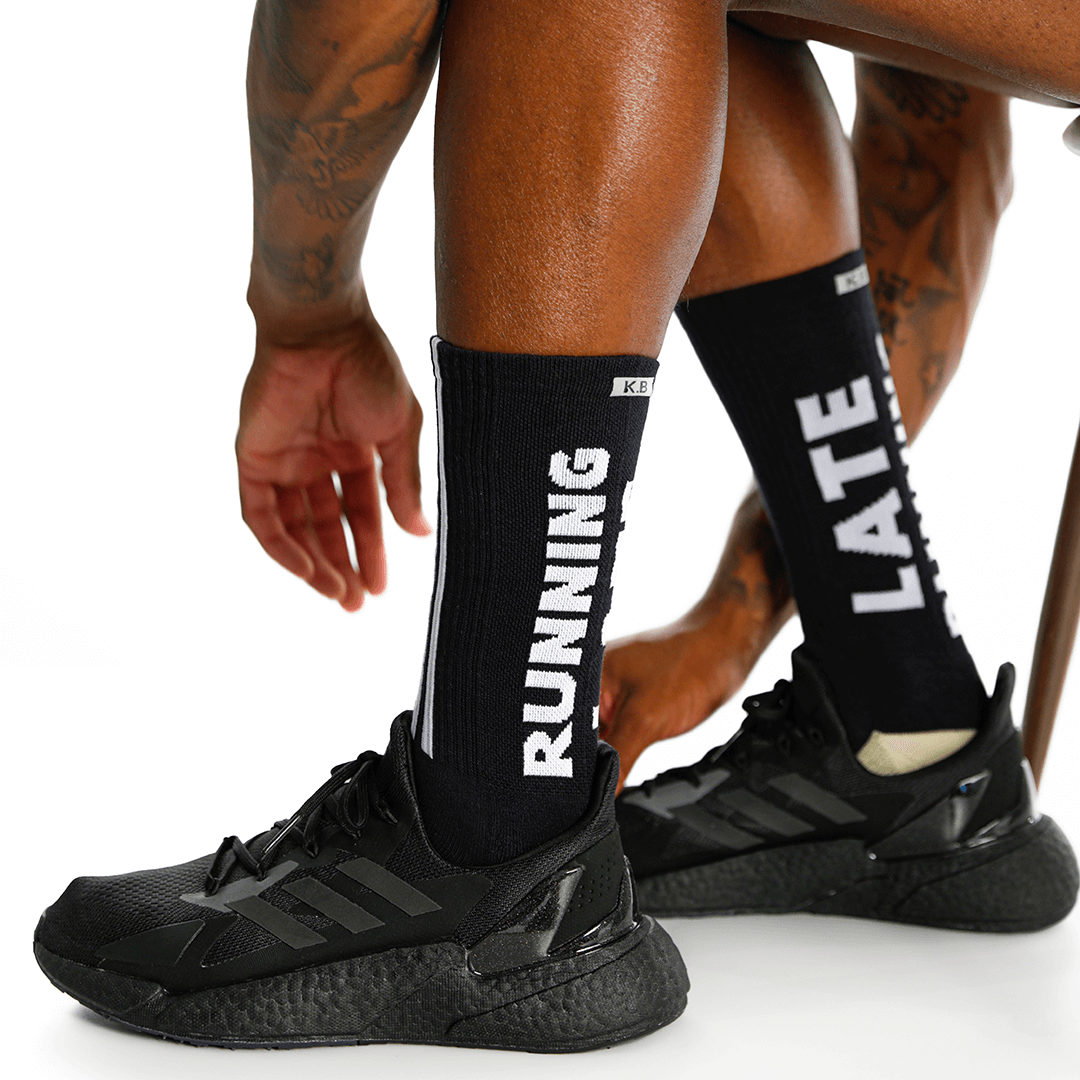 Person wearing black running shoes and socks with text on a white background
