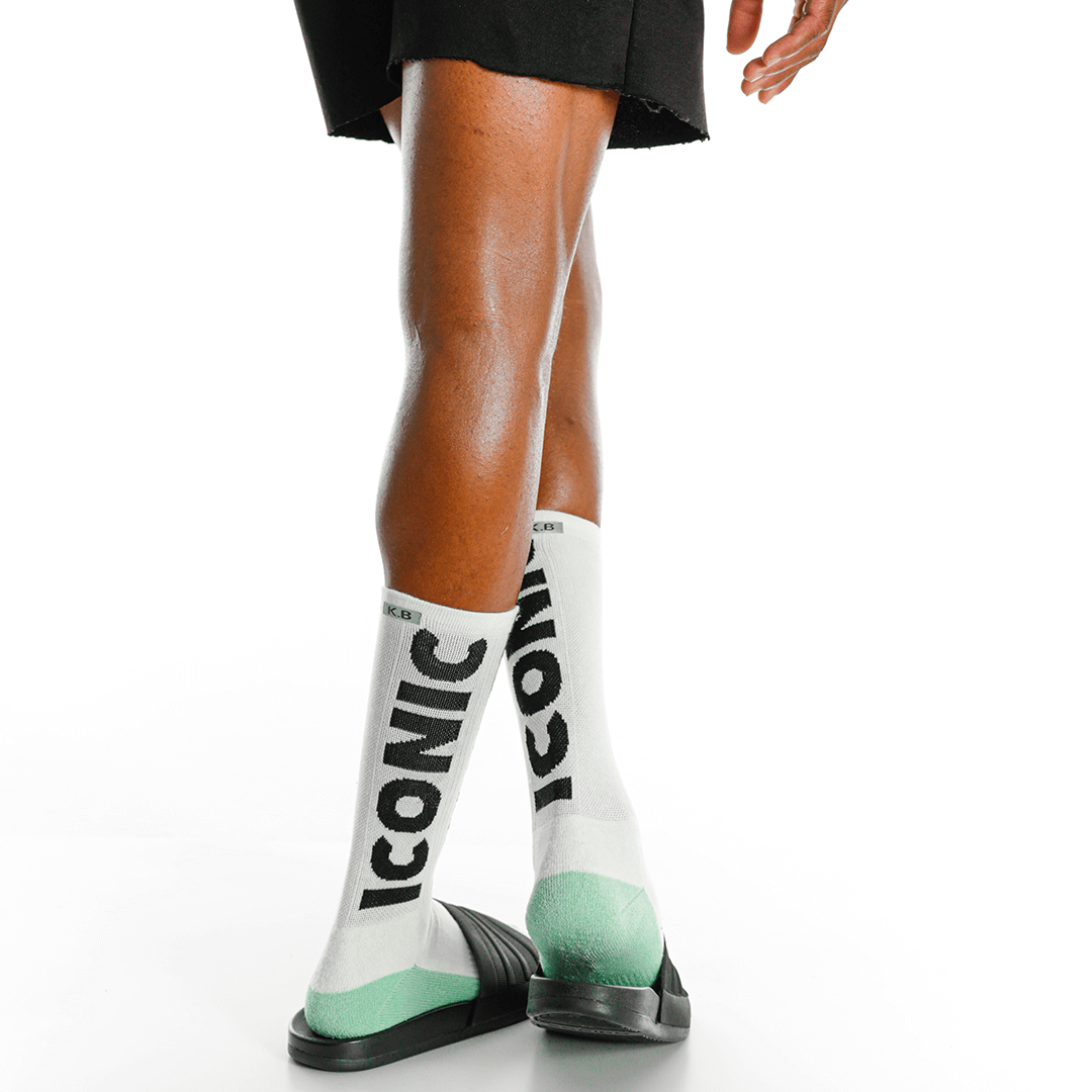 White socks with 'Iconic' text and green accents worn by a person on a white background