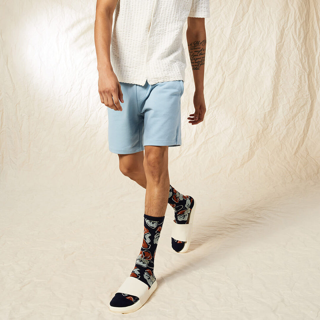 Person wearing light blue shorts and patterned socks on a neutral background