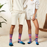 Two people wearing matching white outfits with colorful socks in a casual setting. thumbnail