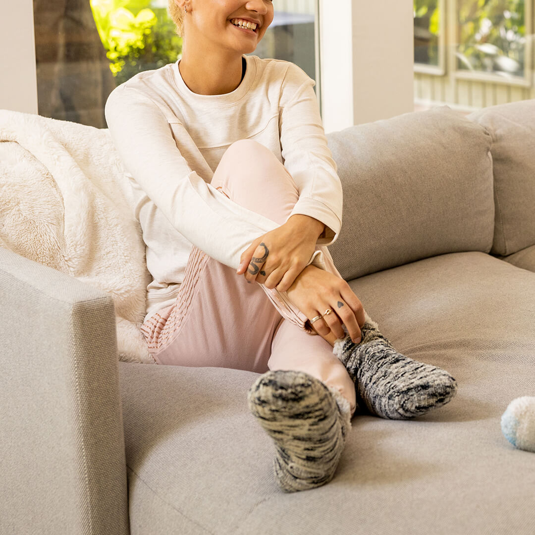 Person sitting on a couch wearing cozy slippers in a home setting