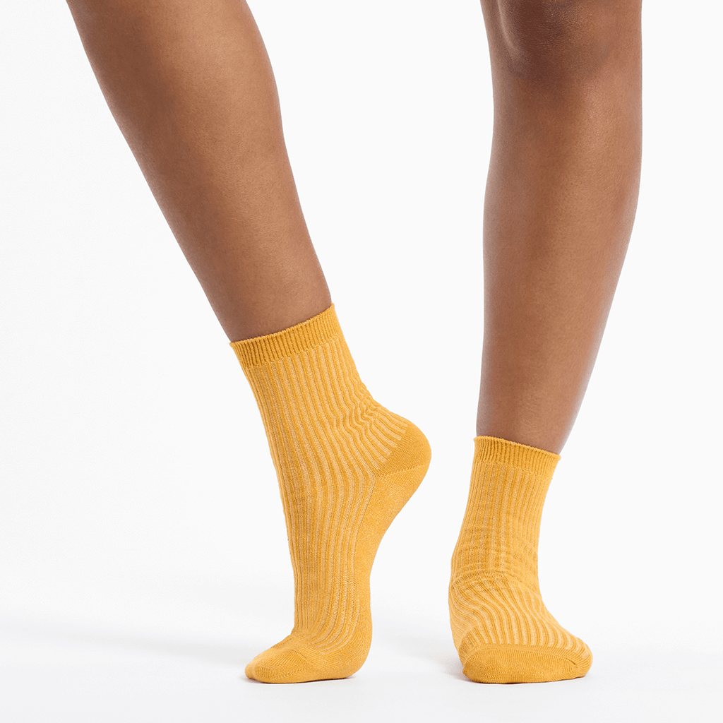 Metallic gold socks worn by a person on a white background
