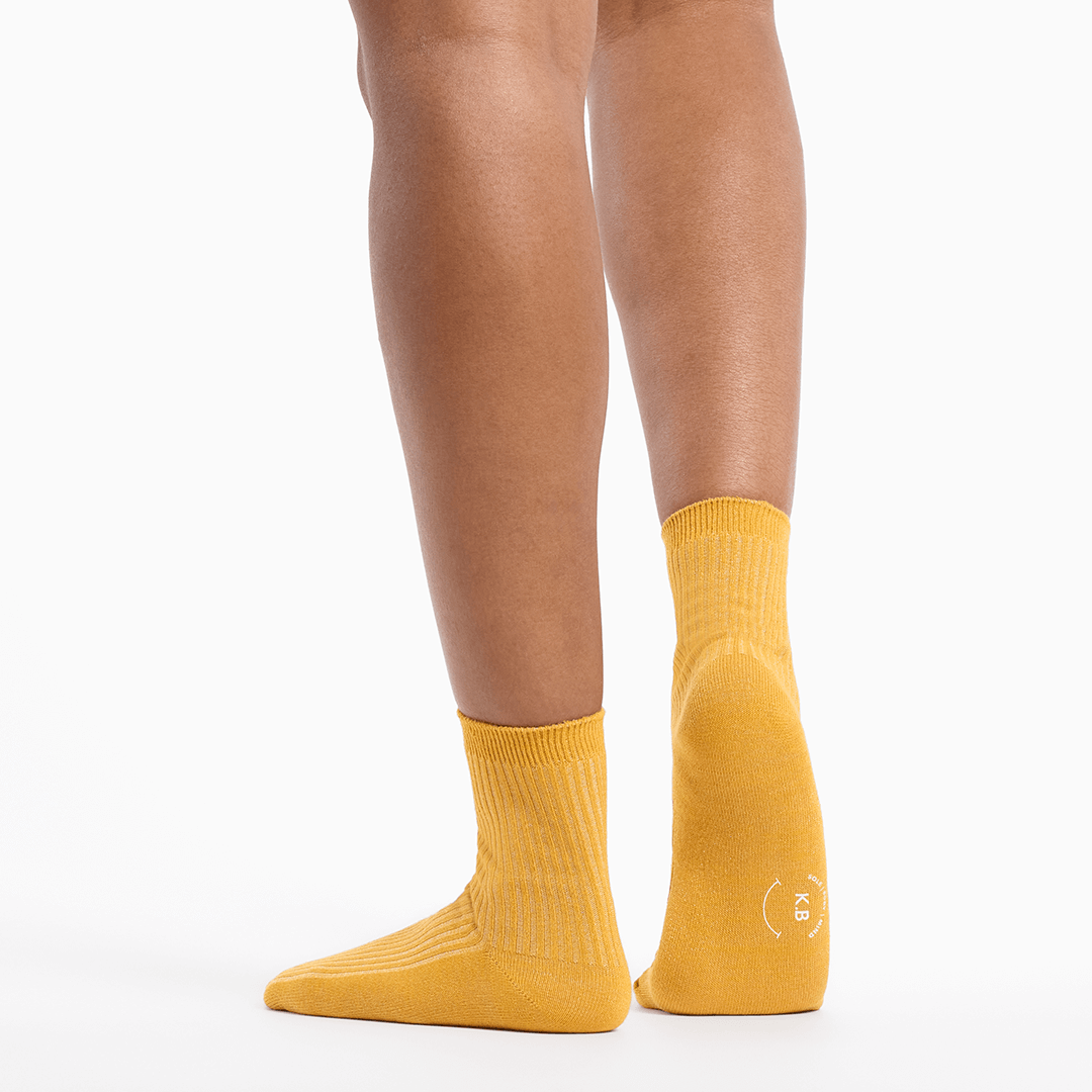 Metallic gold socks worn by a person on a white background
