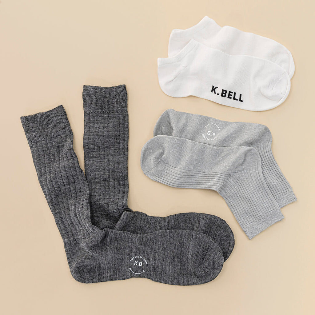 Gray knee-high socks and gray and white ankle socks with K. Bell branding on a beige background