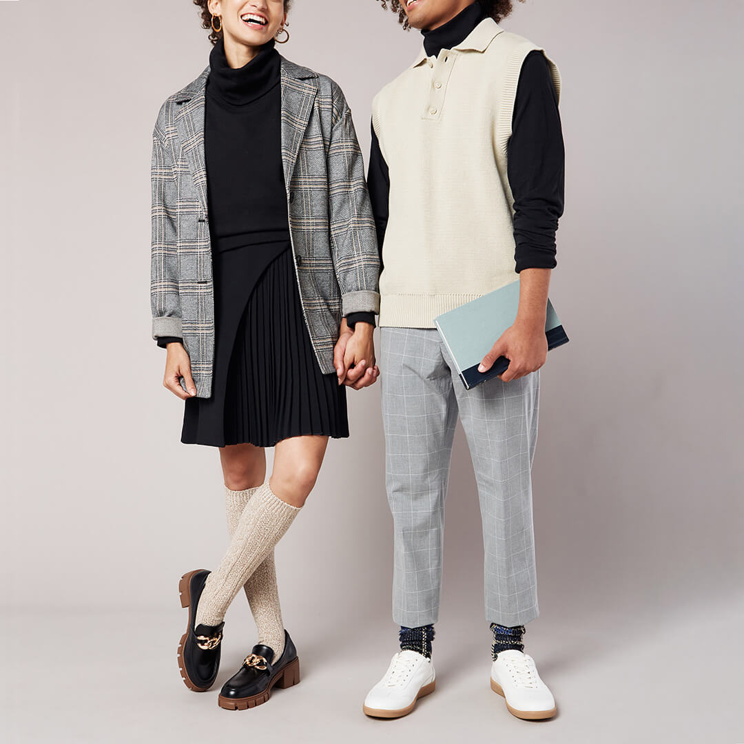 Two people wearing stylish outfits against a plain background
