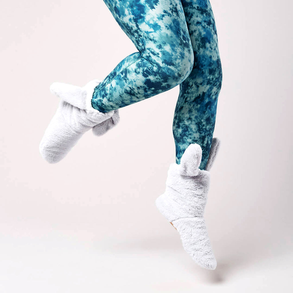 Blue tie-dye leggings worn by a person on a light pink background