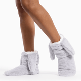 Gray fuzzy slippers worn by a person on a white background