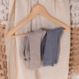 Three pairs of socks on a wooden hanger against a textured beige background