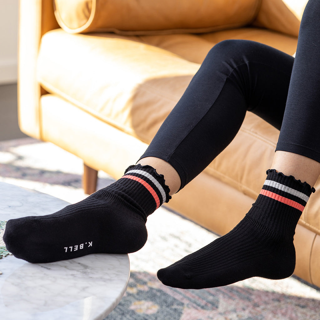 Person wearing black socks with striped cuffs in a living room setting