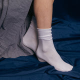White socks worn on a person's feet with a checkered dress and blue velvet in the background thumbnail