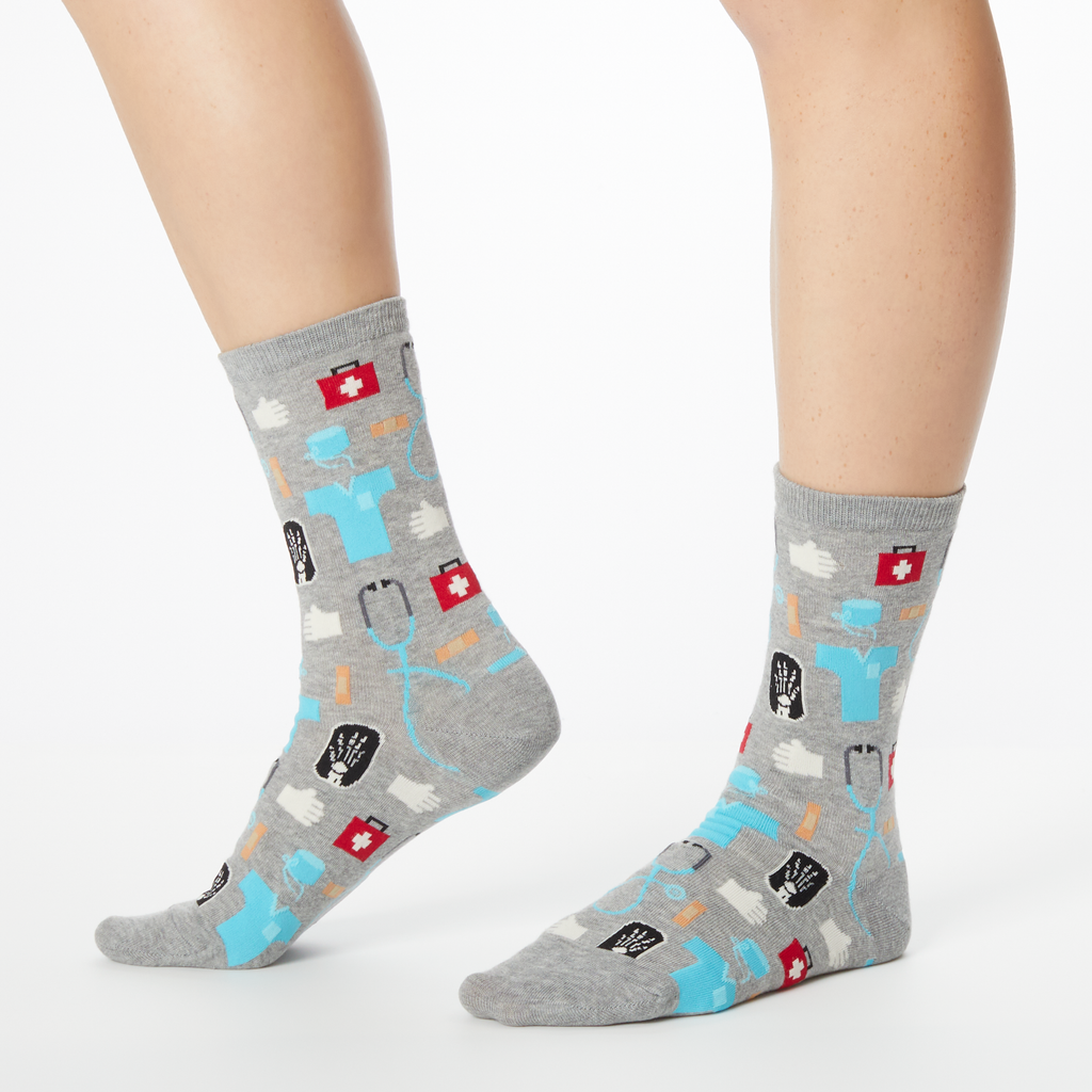 A pair of women's crew socks with a medical supplies print including images of a stethoscope, pills, and a hospital badge.